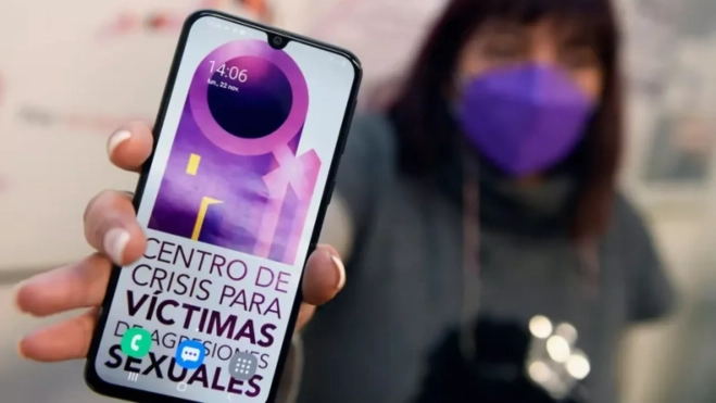 Una mujer sostiene un teléfono que muestra un centro de crisis para atender a las víctimas de violencia sexual / EFE