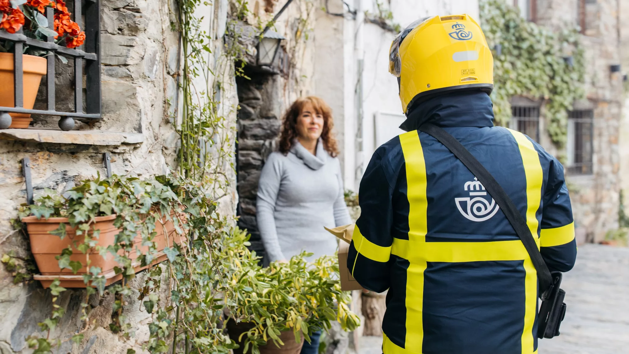 Un trabajador de correos entrega dinero a una mujer en un pueblo / CAIXABANK