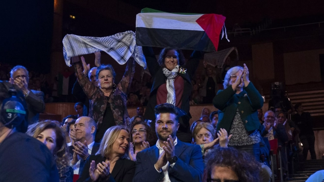 Un grupo de mujeres, presentes en el acto de entrega de Honores y Distinciones del Cabildo de Gran Canaria, ondean banderas y pañuelos palestinos. / AH