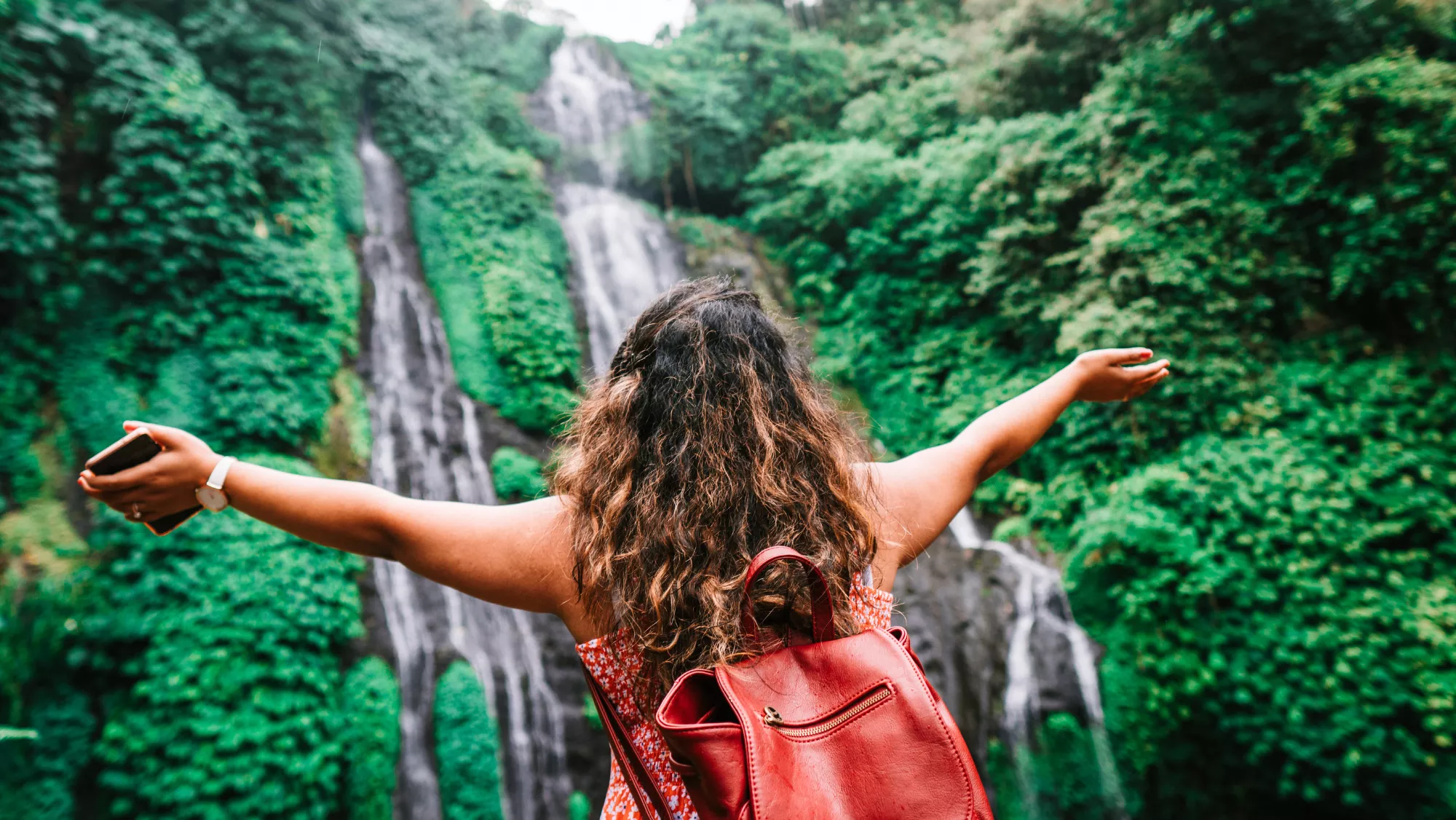 Imagen de una mujer visitando una cascada  AH