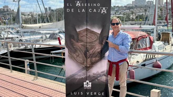 El escritor junto al panel con la portada de su nuevo libro / CEDIDA