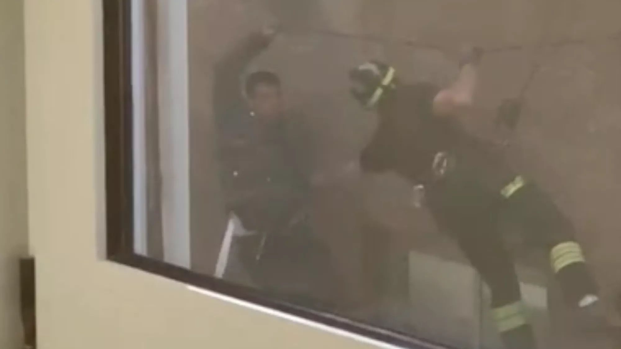 Momento en el que un bombero rescata a un paciente del hospital de La Candelaria que salió por la ventana./ REDES