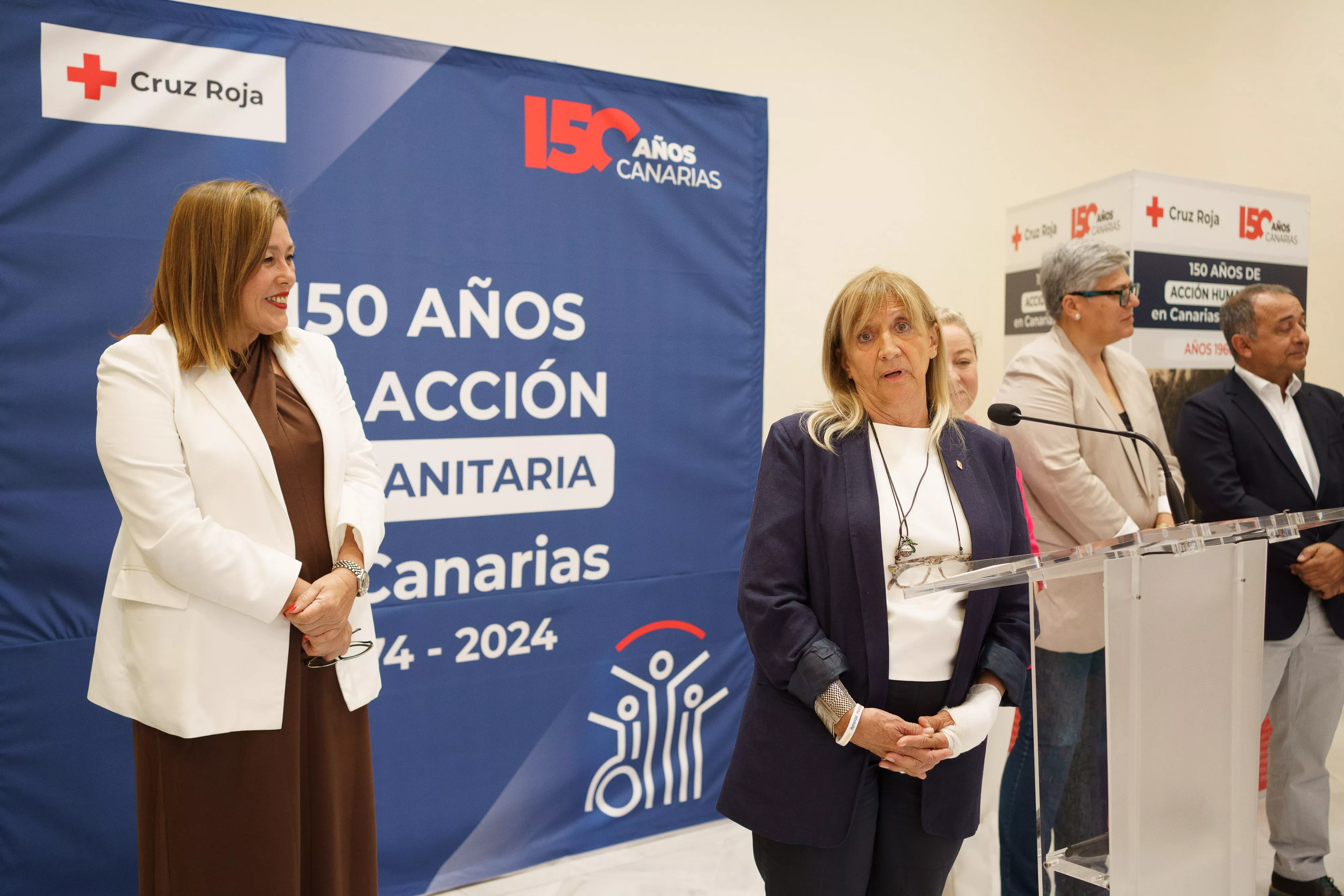 La presidenta de Cruz Roja Canarias, Mayte Pociello (d) junto a la presidenta del Parlamento de Canarias, Astrid Pérez (i), durante la inauguración de la exposición "150 años de acción humanitaria en Canarias". / RAMÓN DE LA ROCHA-EFE