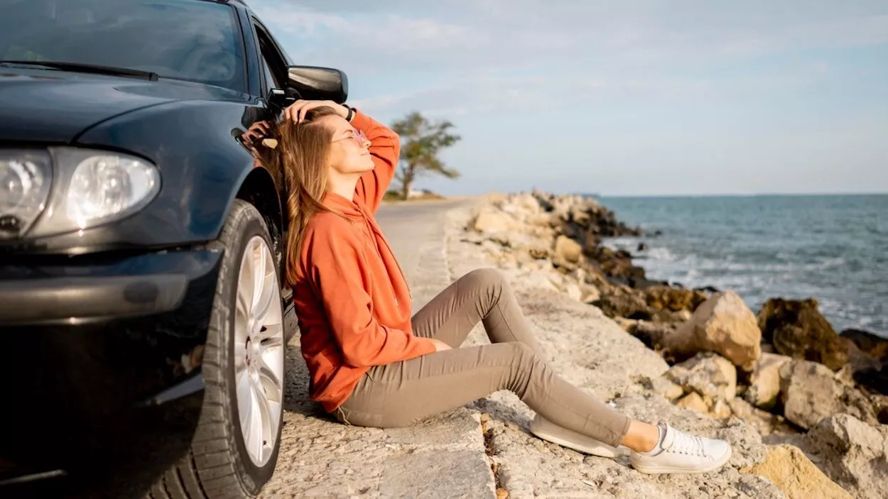 Mujer descansa tomando el sol apoyada en su coche