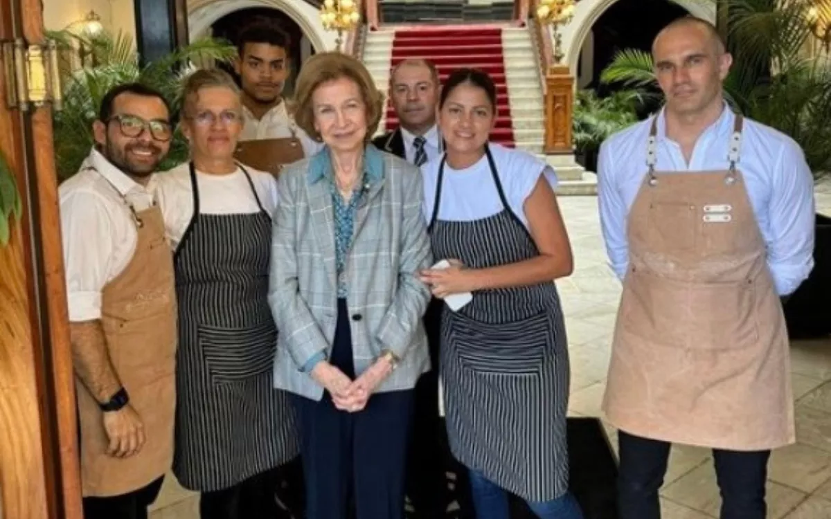 La reina emérita Sofía posa con parte del equipo del restaurante Casa Néstor situado en la entrada del Gabinete Literario. / AH