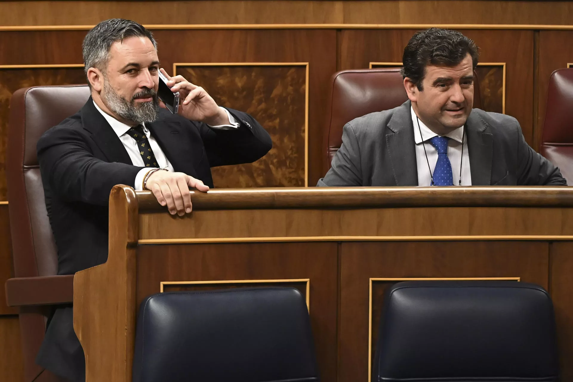 Santiago Abascal, líder de Vox que rechaza el reparto de menores migrantes desde Canarias, habla por teléfono durante un pleno en el Congreso de los diputados. / FERNANDO VILLAR-EFE
