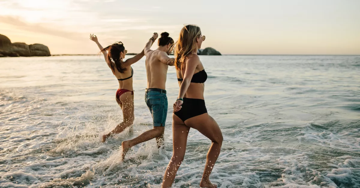 Imagen de tres personas en una playa / AH 