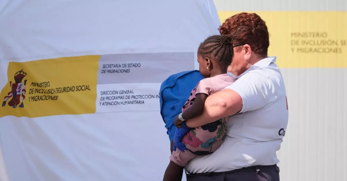 Una voluntaria de Cruz Roja coge en brazos a una menor migrante / EFE