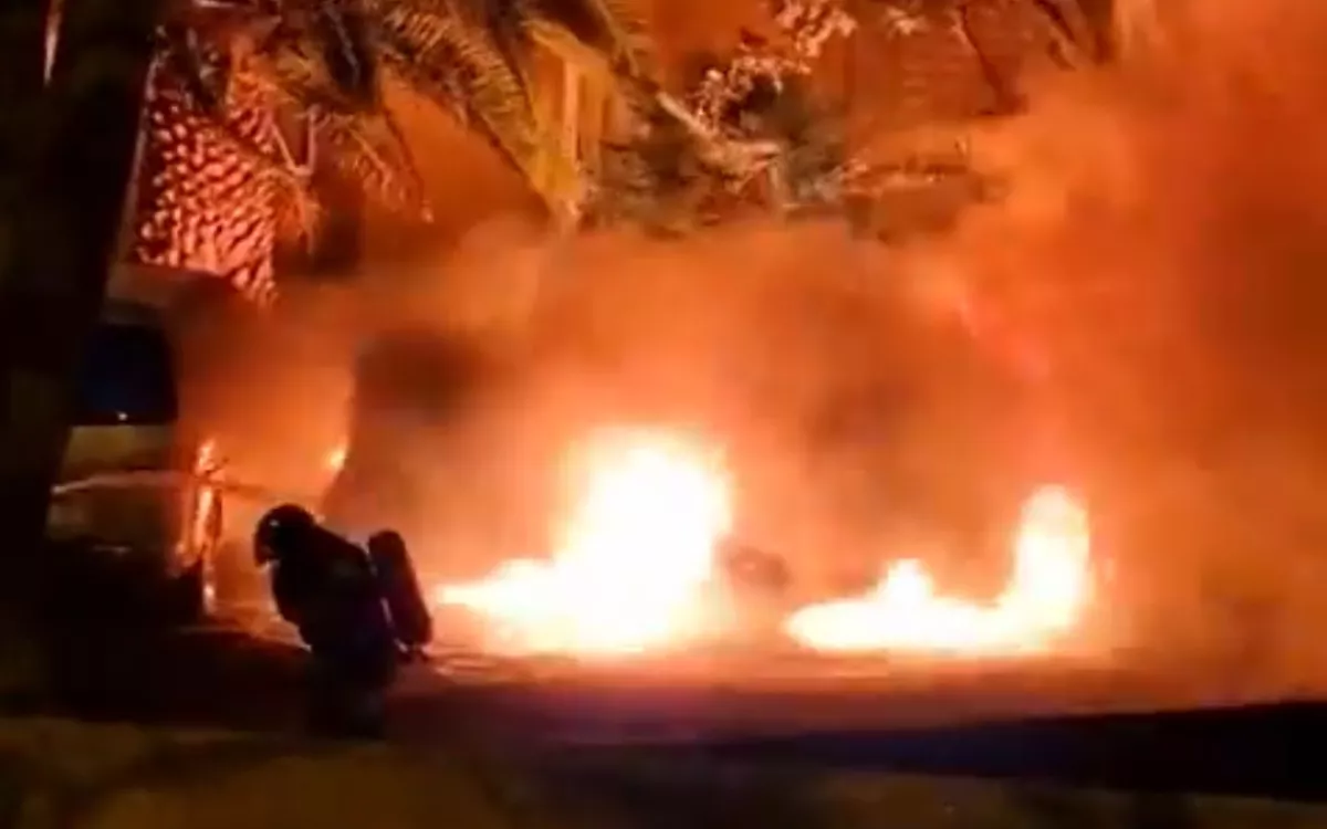 En la imagen, los bomberos intentan sofocar el fuego en uno de los vehículos incendiados en Ofra. / AH