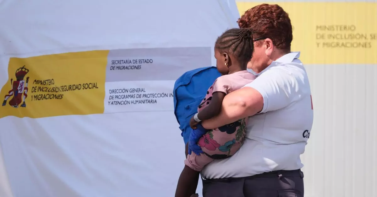 Una menor migrante en brazos de una voluntaria de Cruz Roja / EFE