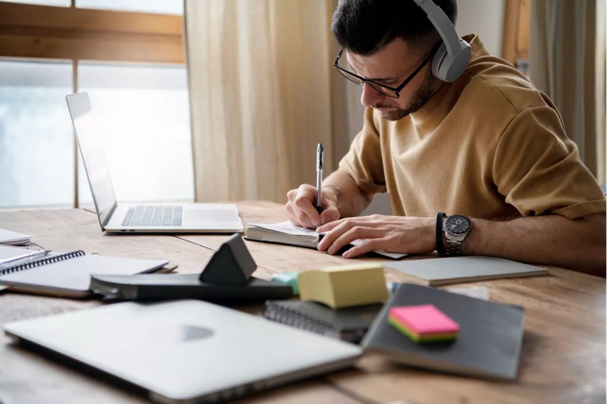 Estudiante escribe con unos cascos puestos / ARCHIVO