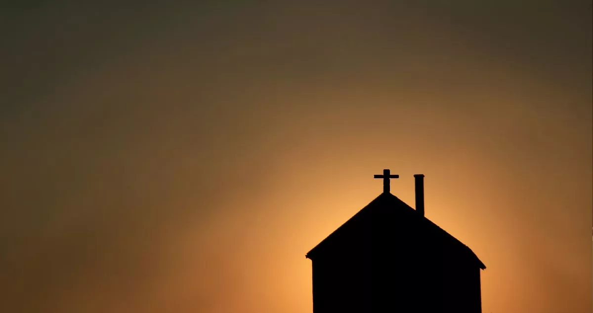 Imagen de archivo de una iglesia y un atardecer / Canva