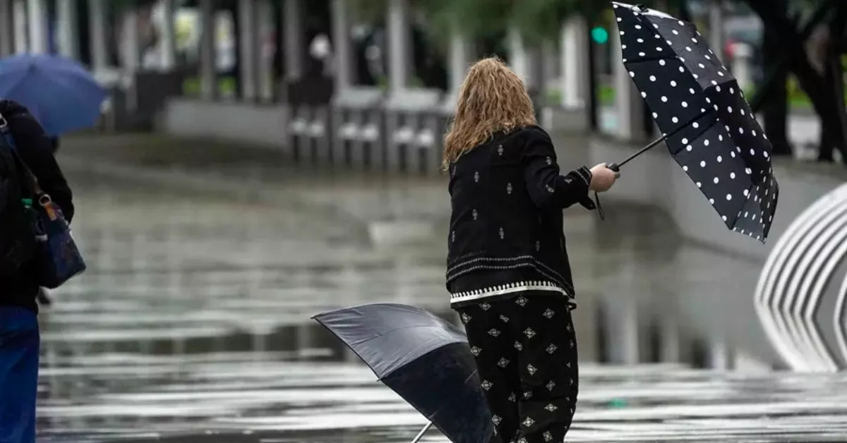 Imagen de una persona bajo la lluvia en una tormenta con dos paraguas / PACO PAREDES - EFE