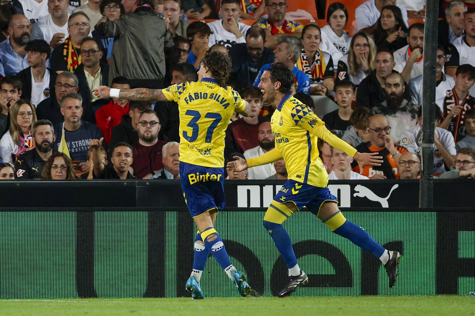 La UD Las Palmas vuelve a ganar y Mestalla arde como una falla. Fabio Silva y Campaña, en la imagen, celebran el segundo gol amarillo. / MANUEL BRUQUE-EFE