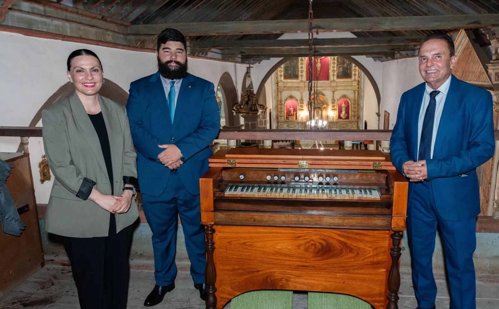 La consejera de Cultura del Gobierno de Canarias, Migdalia Machín; el alcalde de Tinajo, Jesús Machín; y el restaurador Alejandro Jesús Rodríguez Rubio junto al armonio./ CEDIDA