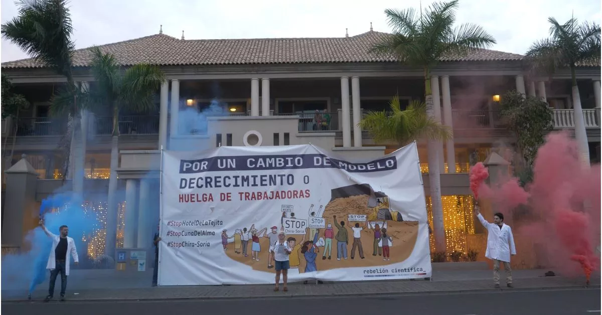 Los activistas, con la pancarta y los botes de humo delante del hotel, en el sur de Tenerife. / REBELIÓN CIENTÍFICA