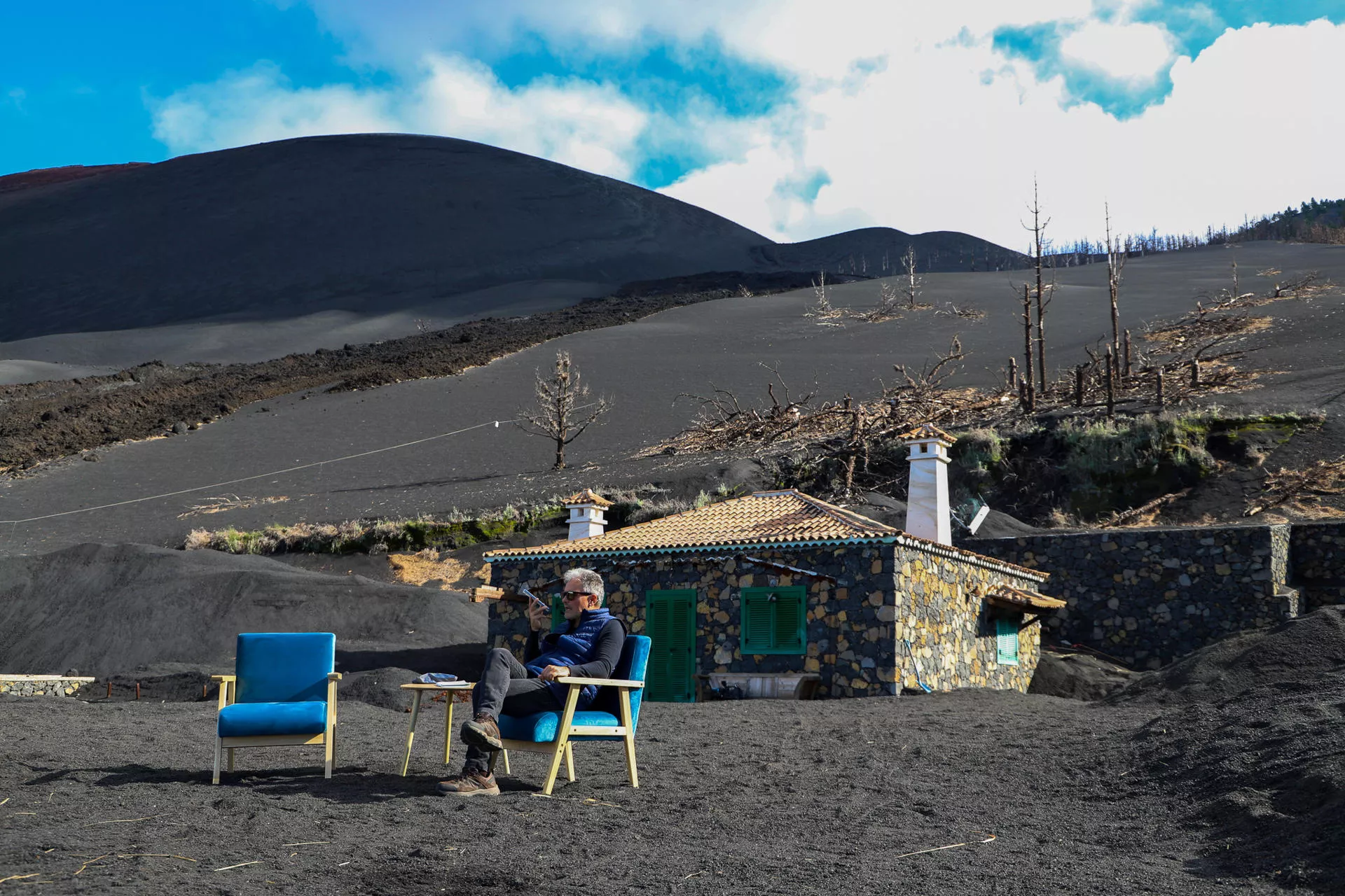 Una casa sepultada por el Tajogaite emerge de la ceniza gracias a una iniciativa solidaria. En la imagen, Vicente Leal posa sentado delante de la vivienda. / LUIS G. MORERA-EFE Una casa sepultada por el Tajogaite emerge de la ceniza gracias a una iniciativa solidaria. En la imagen, Vicente Leal posa sentado delante de la vivienda. / LUIS G. MORERA-EFE