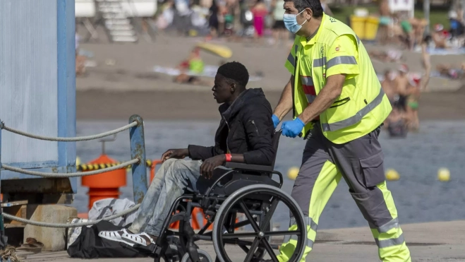 Uno de los migrantes que llegaron a Tenerife, asistido por un sanitario. / MIGUEL BARRETO-EFE Uno de los migrantes que llegaron a Tenerife, asistido por un sanitario. / MIGUEL BARRETO-EFE