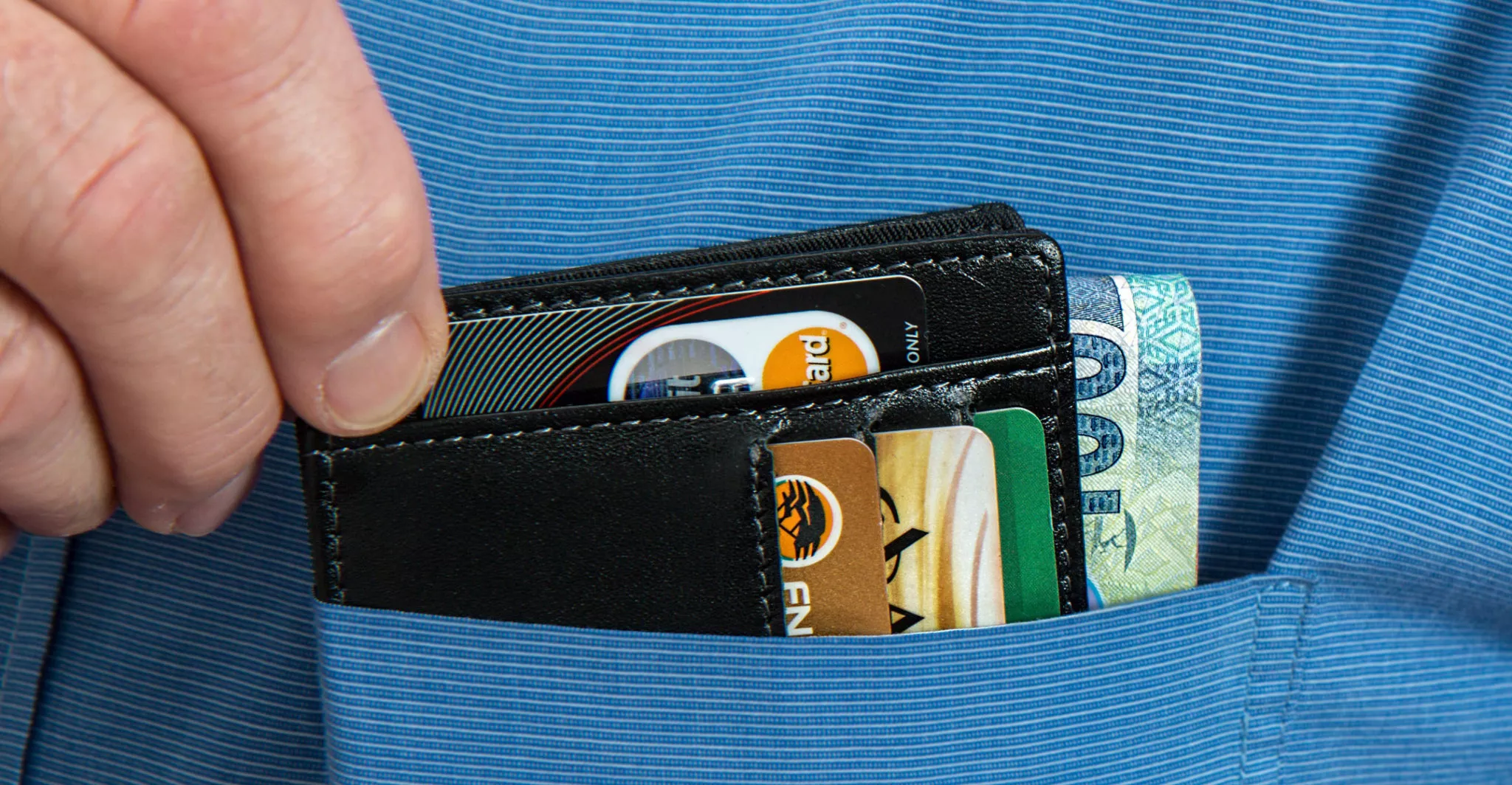 Cartera con tarjetas y dinero en un bolsillo. / ARCHIVO