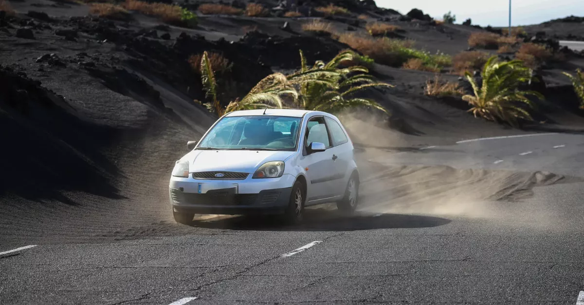 Un coche circula en La Palma junto a montañas de ceniza / EFE