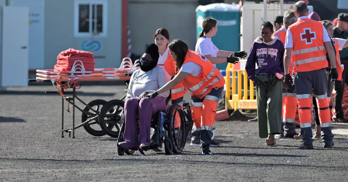 Dos trabajadoras de Cruz Roja ayudan a uno de los migrantes rescatados en la tarde de este martes tras llegar en cayuco / EFE - GELMERT FINOL