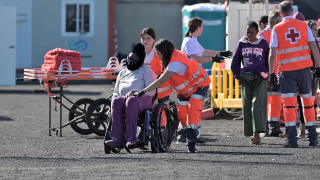 Dos trabajadoras de Cruz Roja ayudan a uno de los migrantes rescatados en la tarde de este martes tras llegar en cayuco / EFE - GELMERT FINOL