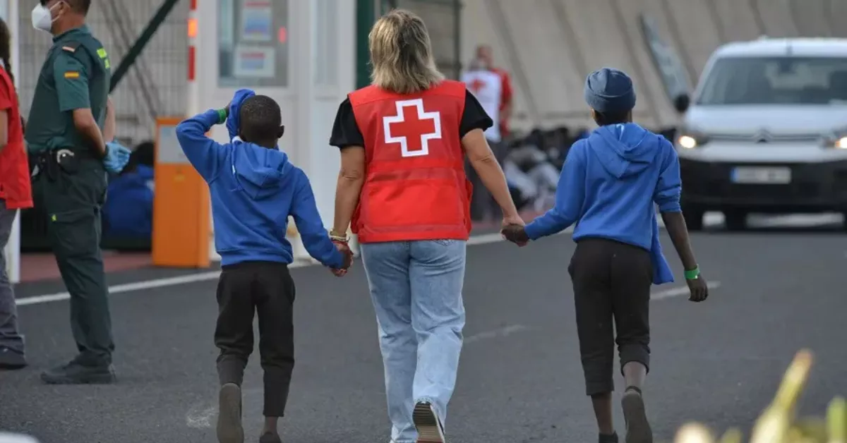 Una trabajadora de Cruz Roja con dos menores llegados a Canarias. / EFE