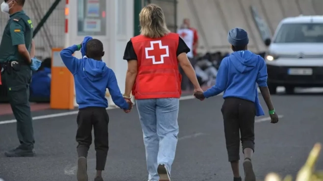 Una trabajadora de Cruz Roja con dos menores llegados a Canarias. / EFE