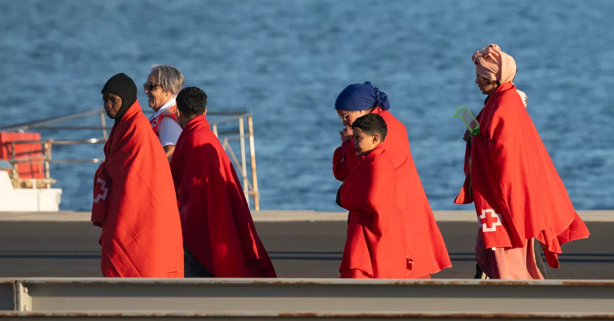 Tres mujeres y dos menores inmigrantes tras desembarcar en el puerto de Arrecife. / EFE