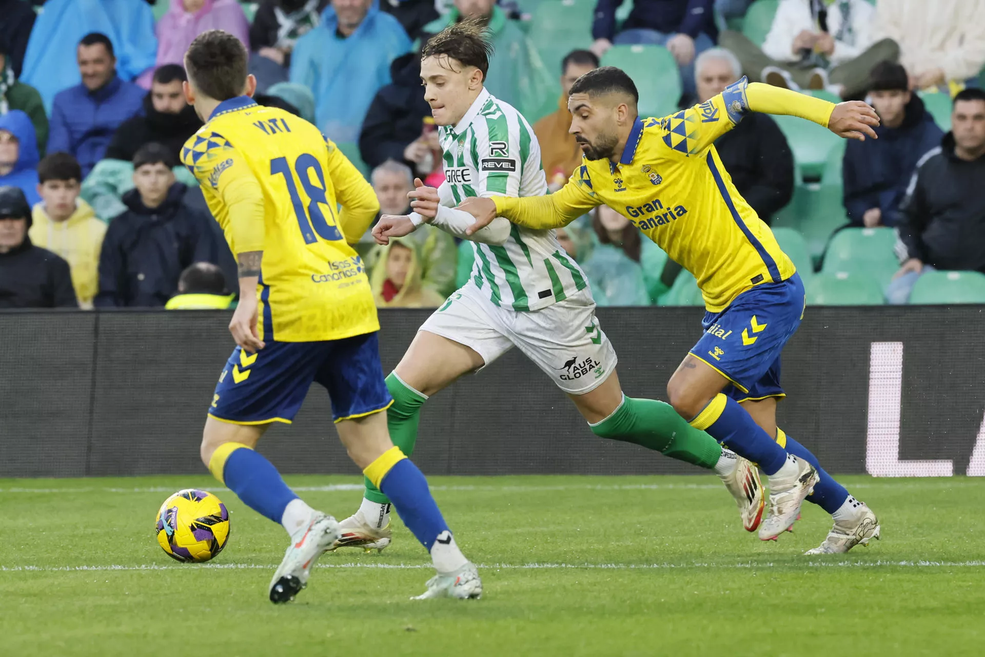 Jesús Rodriguez (c), del Betis, se escapa con el balón durante el partido de LaLiga que Real Betis y UD Las Palmas disputan hoy domingo en el Benito Villamarín, en Sevilla. / EFE - JOSÉ MANUEL VIDAL