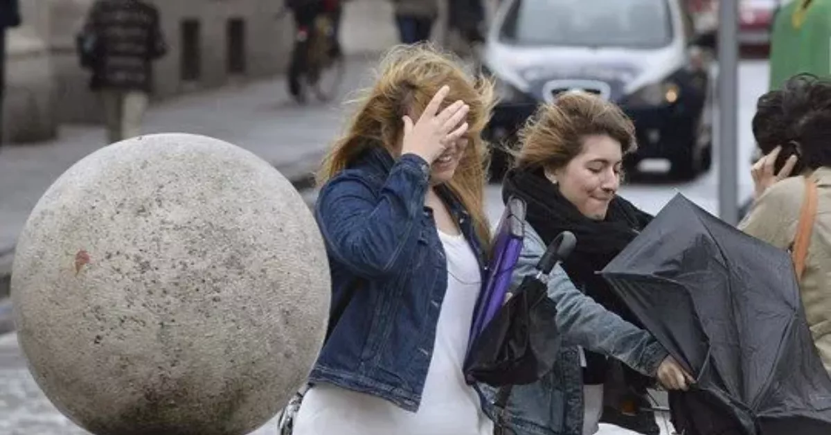 Imagen de dos personas lidiando con el viento / EFE