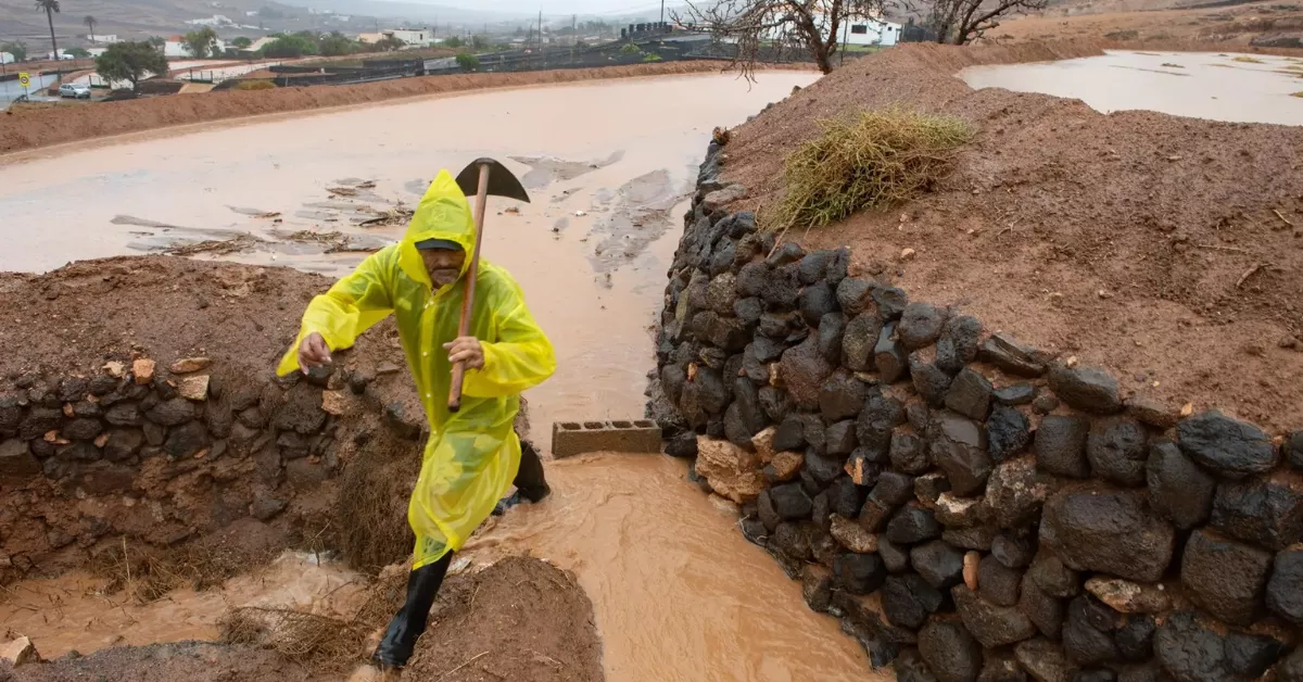 Imagen de un hombre en medio de una borrasca con fuertes lluvias / EFE