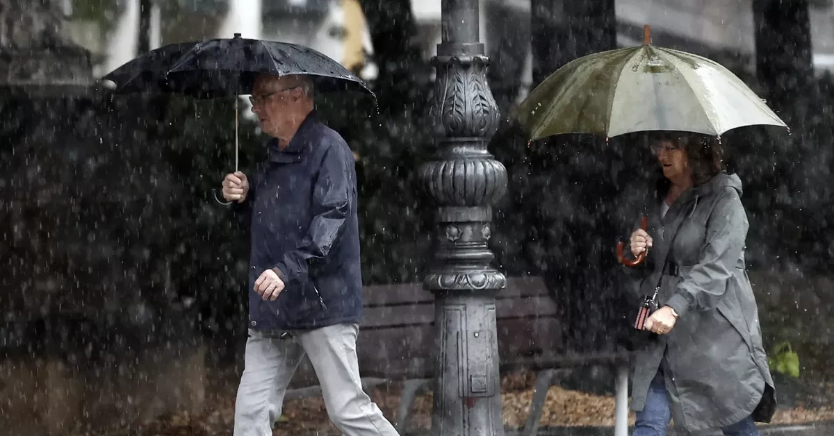 Imagen de dos personas caminando bajo la lluvia / EFE