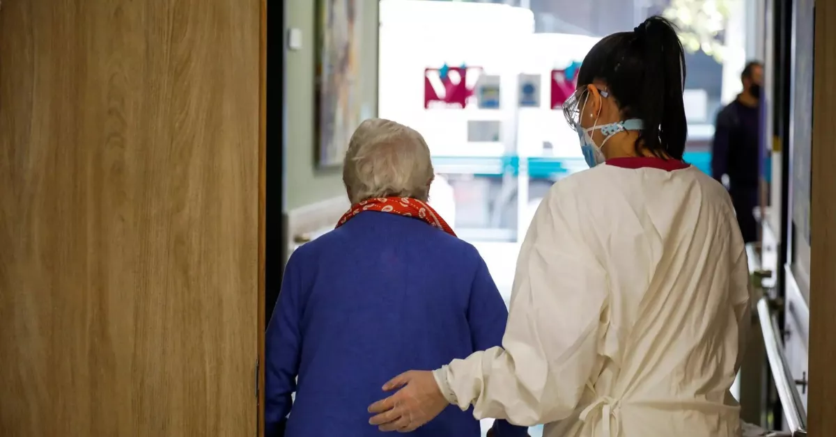 Una profesional sanitaria acompaña a una persona en situación de Dependencia. / EFE - DAVID FERNÁNDEZ