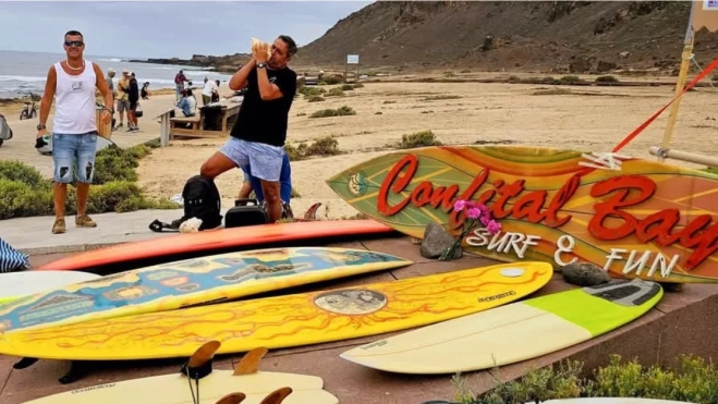 Un momento del homenaje al 'Bisnieto', con la llamada al mar y el cartel de la mítica tienda Confital Bay. / ROMPEOLAS SURF MAGAZINE