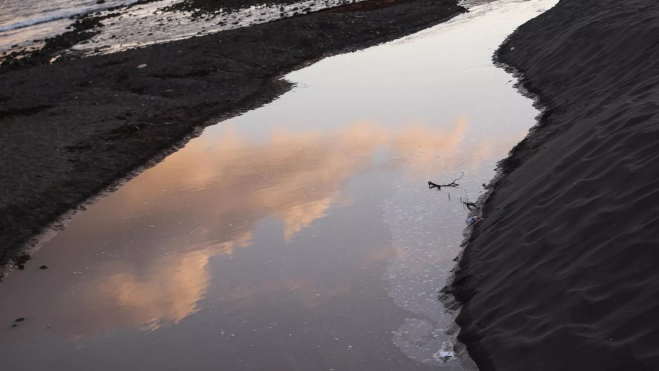 Vertido de agua en una de las playas cerradas en Adeje. / ALBERTO VALDÉS-EFE