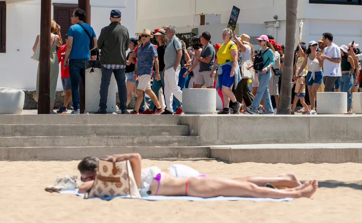 Dos personas en la playa cerca de los manifestantes en Canarias / EFE