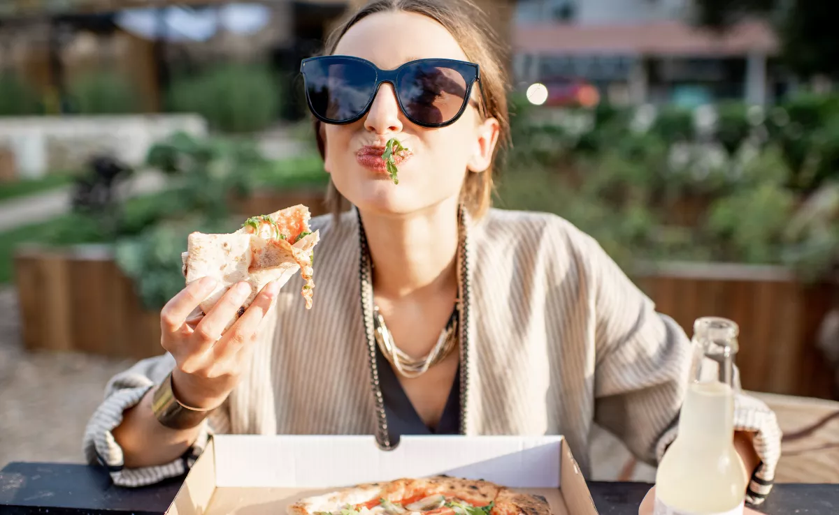 Imagen de una persona comiendo una pizza / PEXELS