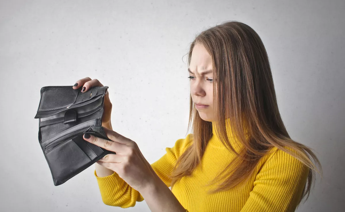 Imagen de una persona mirando una cartera vacía / PEXELS