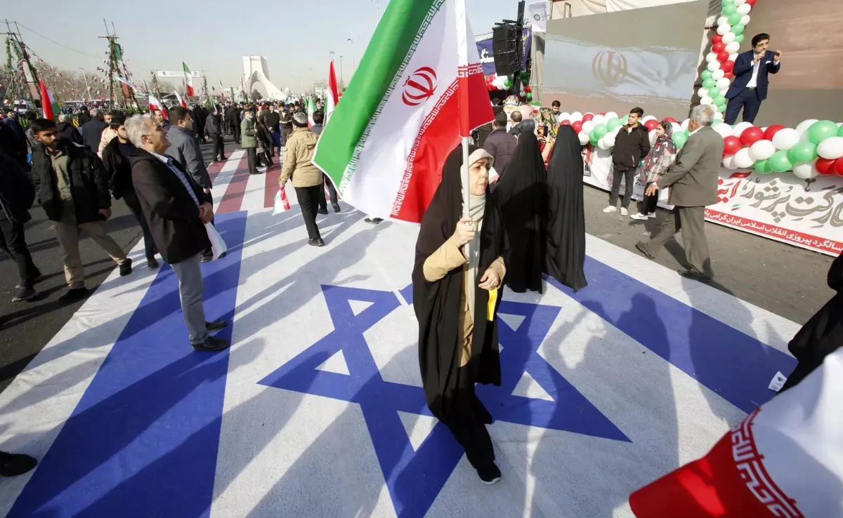 Una mujer iraní sostiene la bandera nacional de Irán mientras camina sobre la bandera de Israel, en una fotografía de archivo / EFE - Abedin Taherkenareh