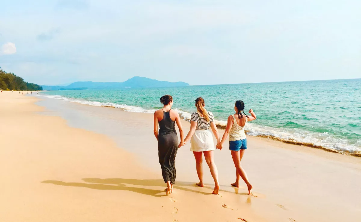 Imagen de tres personas en una playa / PEXELS