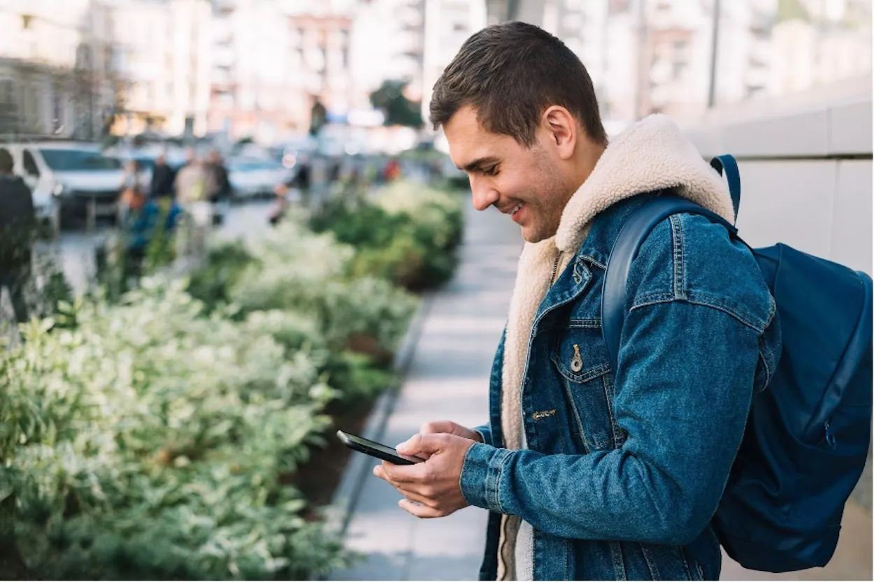 Viajero con mochila utiliza un teléfono móvil/ FREEPIK