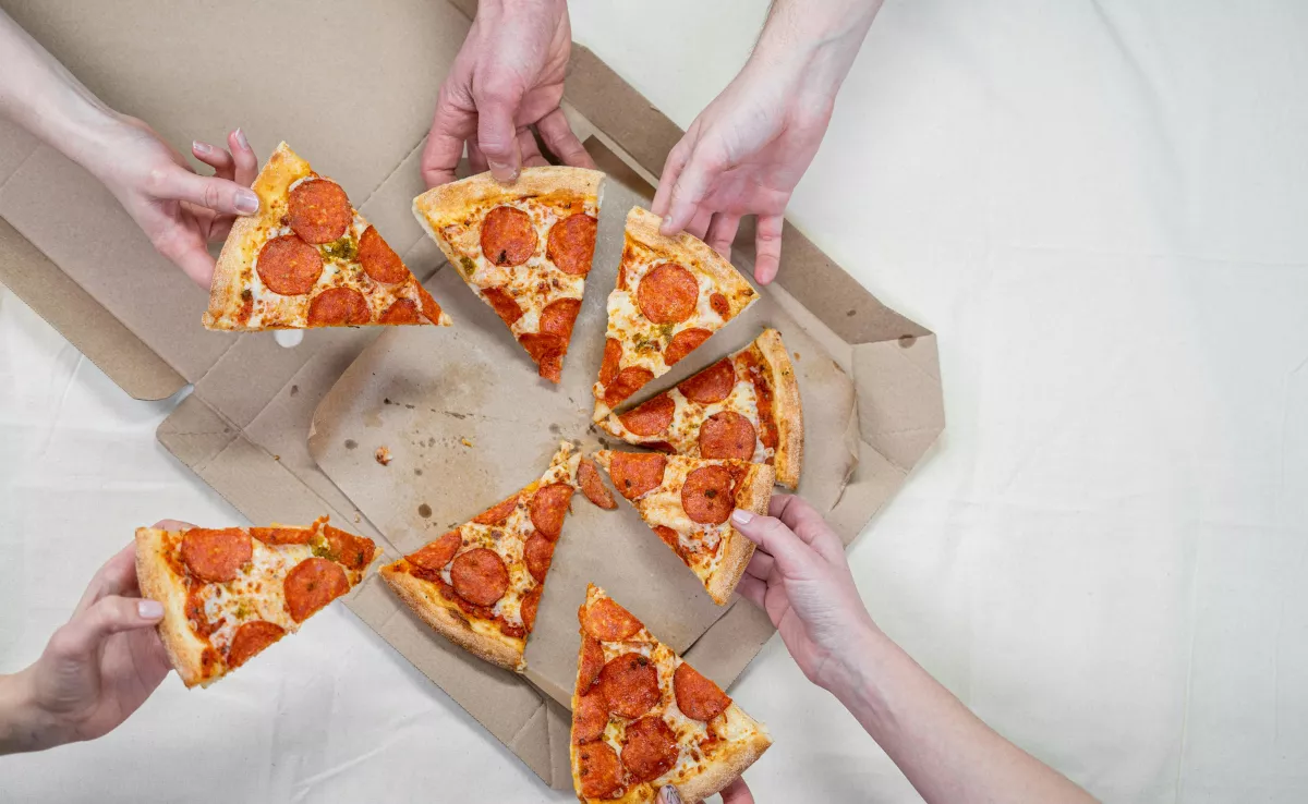 Imagen de un grupo de amigos comiendo pizzas / PEXELS