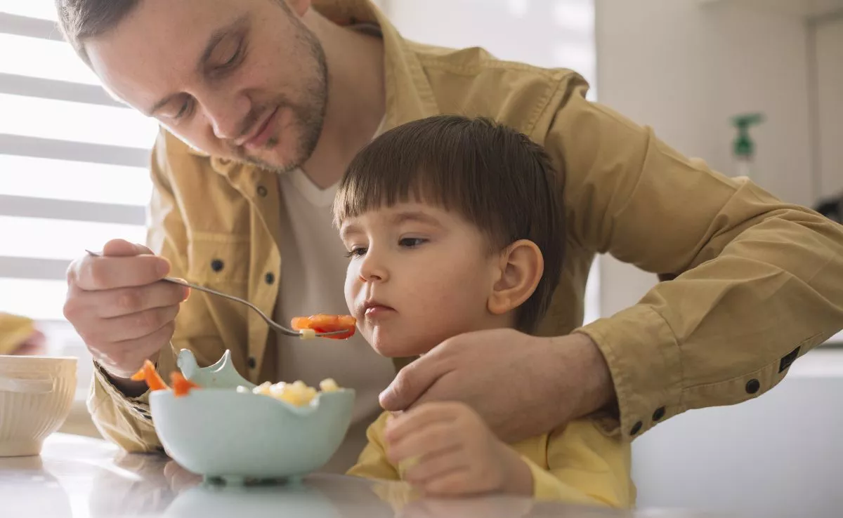 Padre dando de comer a su hijo. /Freepik
