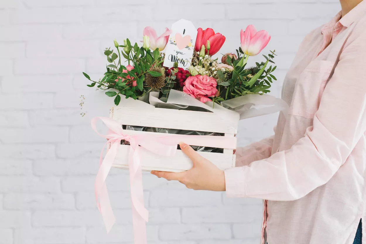 Una mujer con una caja de flores para regalo FREEPIK