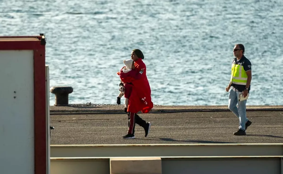 Mujer migrante camina con un bebé en brazos en zona de un puerto de Canarias. Imagen de archivo. /EFE