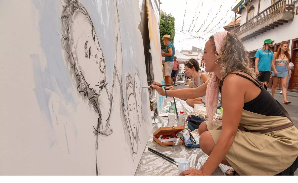 Varias artistas dan forma a sus obras en la calle principal del pueblo, que ya se prepara para La Rama. / NACHO GONZÁLEZ ORAMAS