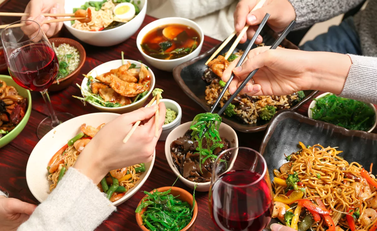 Un grupo de personas comiendo comida china en un restaurante / CANVA