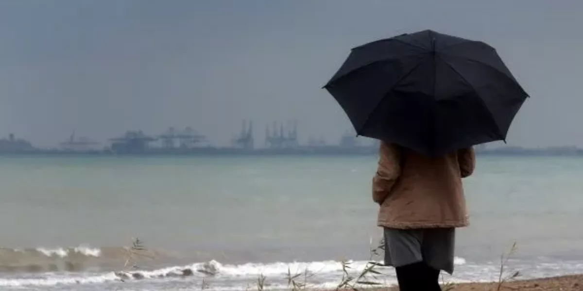 Imagen de una persona frente al mar en un día de lluvia / EFE