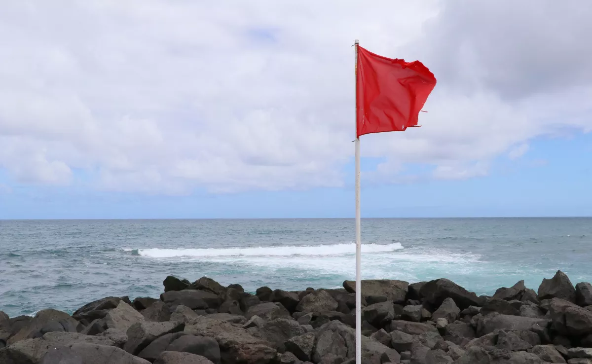 Imagen de una playa con bandera roja / CANVA